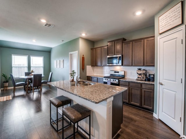 519 Stampede Ln, Princeton, TX 75407 - kitchen with appliances with stainless steel finishes, a sink, light stone countertops, dark wood-type flooring, and a breakfast bar