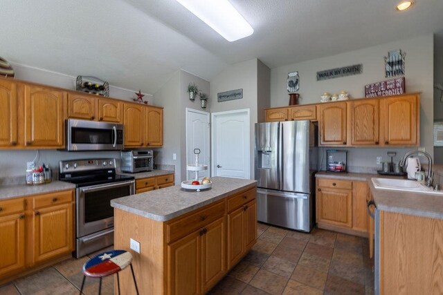 1551 Whiterock Dr, Midlothian, TX 76065 - kitchen featuring appliances with stainless steel finishes, a sink, vaulted ceiling, light countertops, and a center island