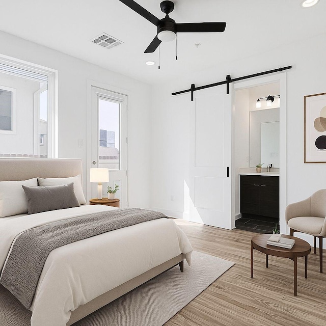 2235 Lovedale Ave Unit 102, Dallas, TX 75235 - bedroom featuring a barn door, light wood-style flooring, ensuite bathroom, recessed lighting, and ceiling fan