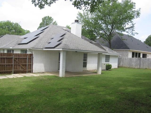 101 Ginger Dr, Pottsboro, TX 75076 - back of house with a patio, a chimney, brick siding, a shingled roof, and roof mounted solar panels