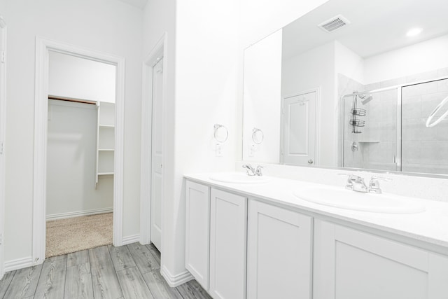 624 Beltrand Ln, Fate, TX 75087 - bathroom featuring a stall shower, double vanity, a walk in closet, and wood finished floors