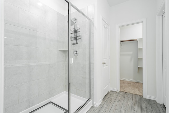 624 Beltrand Ln, Fate, TX 75087 - bathroom with a stall shower, wood finished floors, a walk in closet, and baseboards