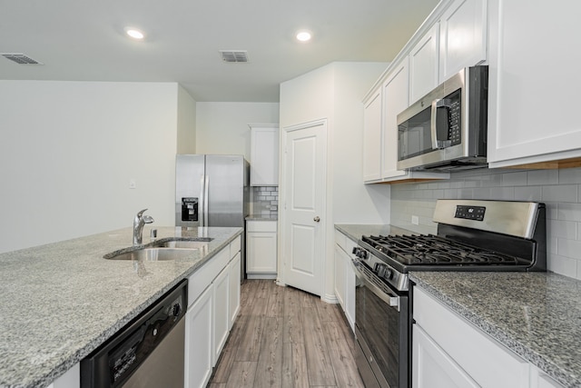 624 Beltrand Ln, Fate, TX 75087 - kitchen featuring appliances with stainless steel finishes, a sink, light wood finished floors, white cabinets, and recessed lighting