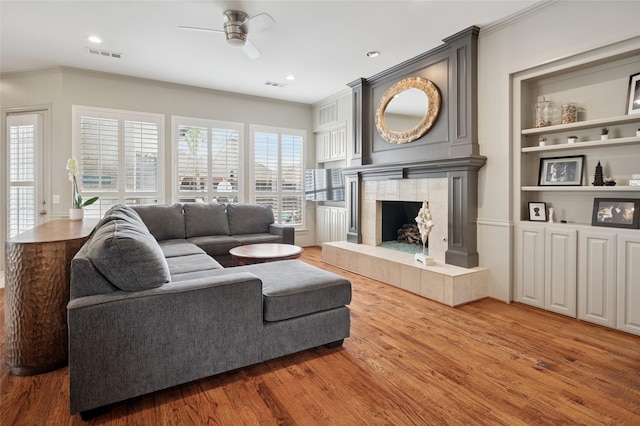 3908 Sagamore Hill Ct, Plano, TX 75025 - living room with ornamental molding, a ceiling fan, wood finished floors, a fireplace, and built in shelves