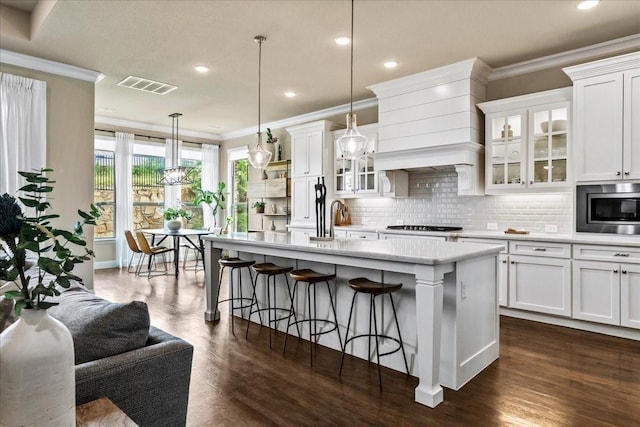 3480 Newport Dr, Prosper, TX 75078 - kitchen with ornamental molding, stainless steel microwave, dark wood-type flooring, backsplash, and a kitchen bar