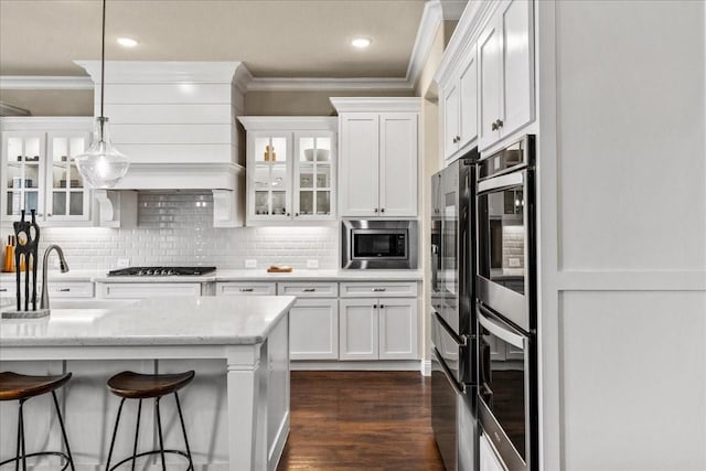 3480 Newport Dr, Prosper, TX 75078 - kitchen featuring stainless steel appliances, crown molding, white cabinetry, glass insert cabinets, and tasteful backsplash