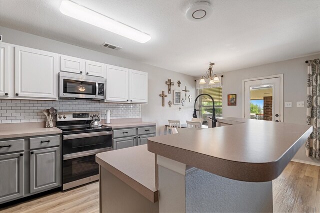1036 Ridgetop Dr, Justin, TX 76247 - kitchen with stainless steel appliances, gray cabinets, light wood-style floors, and decorative backsplash