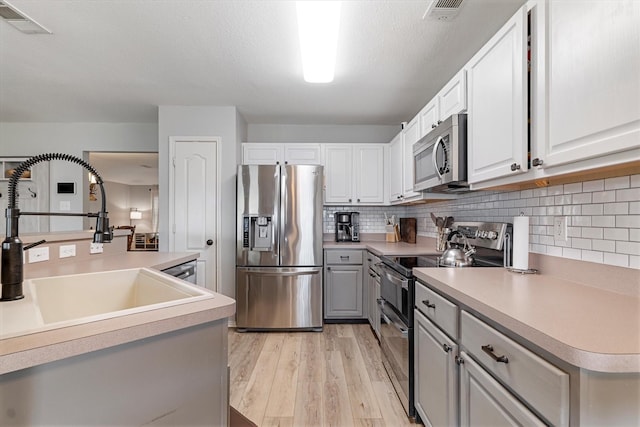 1036 Ridgetop Dr, Justin, TX 76247 - kitchen featuring stainless steel appliances, light wood finished floors, tasteful backsplash, a sink, and light countertops