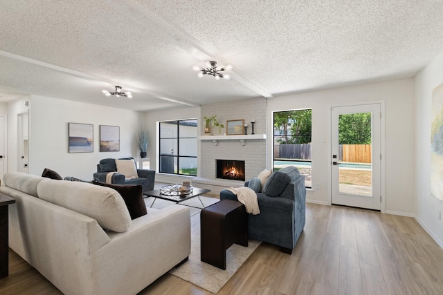 2609 Peppertree Pl, Plano, TX 75074 - living area featuring a textured ceiling, light wood-style floors, a brick fireplace, a chandelier, and baseboards