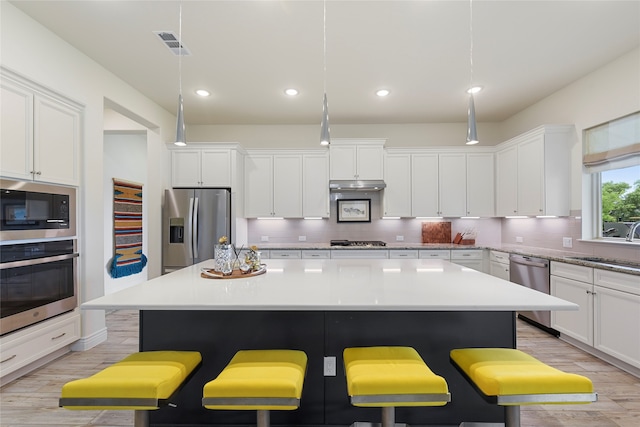 11017 Cartwright Dr, Denton, TX 76207 - kitchen with stainless steel appliances, a breakfast bar, a center island, light wood-type flooring, and backsplash