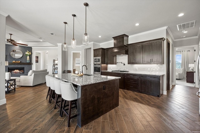 1007 Sinopa St, Caddo Mills, TX 75135 - kitchen featuring stainless steel appliances, ornamental molding, a ceiling fan, a brick fireplace, and custom range hood