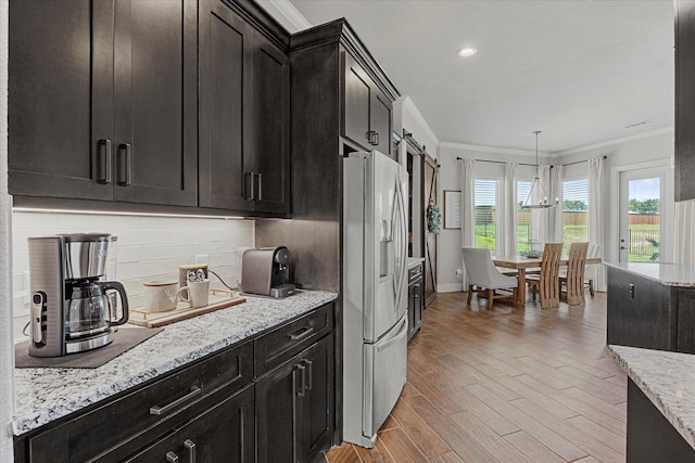 1007 Sinopa St, Caddo Mills, TX 75135 - kitchen with stainless steel refrigerator with ice dispenser, crown molding, light wood finished floors, tasteful backsplash, and light stone countertops