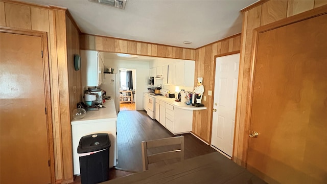 5632 Taylor Rd, River Oaks, TX 76114 - kitchen with white appliances, light countertops, dark wood-style floors, white cabinets, and wood walls