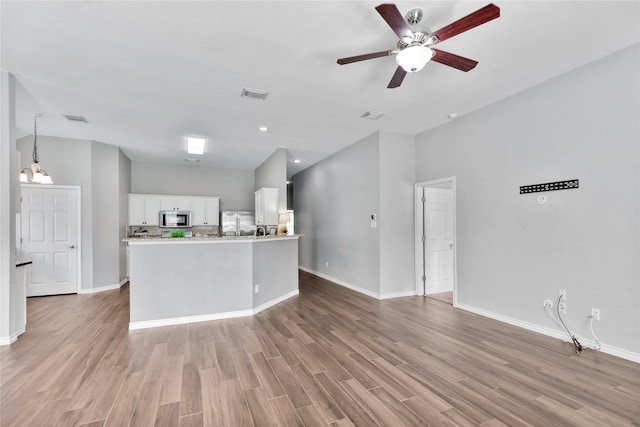 2814 Saddlebred Trl, Celina, TX 75009 - kitchen with stainless steel appliances, light wood-type flooring, white cabinets, open floor plan, and light countertops