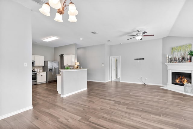2814 Saddlebred Trl, Celina, TX 75009 - unfurnished living room with a glass covered fireplace, wood finished floors, a chandelier, a ceiling fan, and arched walkways