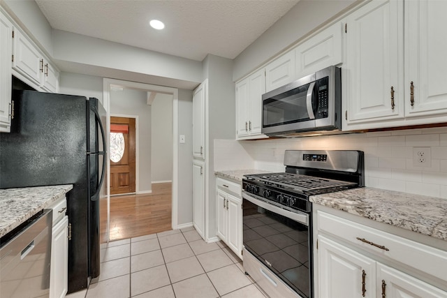 2537 Montclair Ln, Mesquite, TX 75150 - kitchen with appliances with stainless steel finishes, tasteful backsplash, white cabinetry, light stone counters, and baseboards