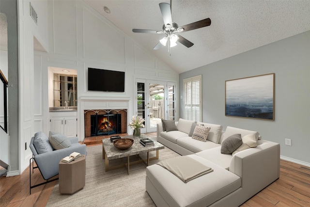 2537 Montclair Ln, Mesquite, TX 75150 - living area featuring wood finished floors, a ceiling fan, a lit fireplace, high vaulted ceiling, and baseboards
