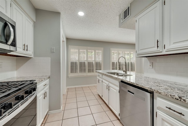 2537 Montclair Ln, Mesquite, TX 75150 - kitchen featuring stainless steel appliances, white cabinetry, decorative backsplash, a sink, and light stone countertops
