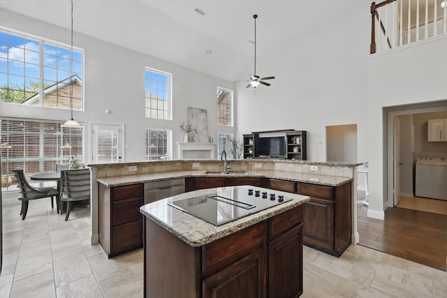 14620 Windsor Ct, Addison, TX 75001 - kitchen featuring a towering ceiling, a kitchen island, a sink, black electric cooktop, and washer / dryer