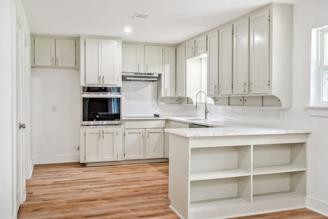 436 Crestwood Ter, Hurst, TX 76053 - kitchen with stainless steel oven, a sink, under cabinet range hood, light countertops, and light wood finished floors