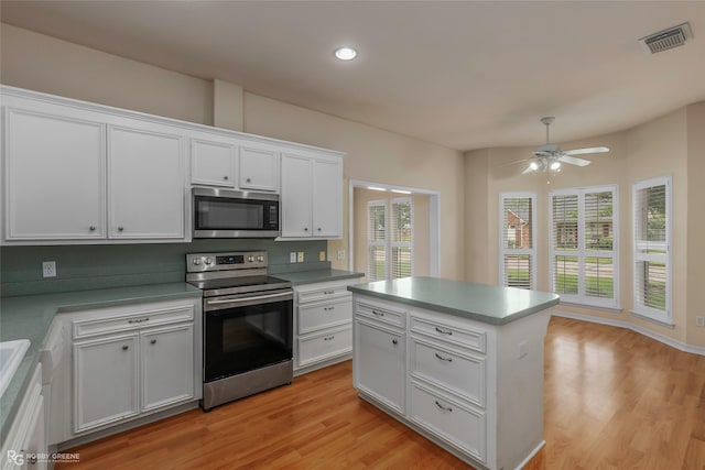 10085 Baldwin Ct, Shreveport, LA 71115 - kitchen featuring stainless steel appliances, white cabinets, ceiling fan, light wood finished floors, and a center island
