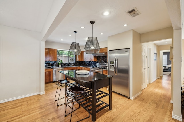 9834 Carnegie Dr, Dallas, TX 75228 - kitchen with appliances with stainless steel finishes, a sink, backsplash, under cabinet range hood, and light wood finished floors