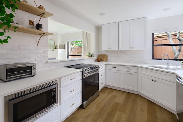 4040 Morman Ln, Addison, TX 75001 - kitchen featuring appliances with stainless steel finishes, open shelves, a sink, and healthy amount of natural light