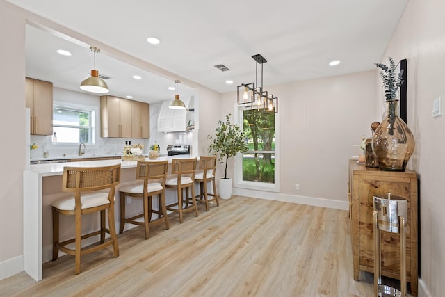 10528 Swallow Ln, Dallas, TX 75218 - kitchen with light wood-type flooring, light countertops, a kitchen breakfast bar, recessed lighting, and a peninsula
