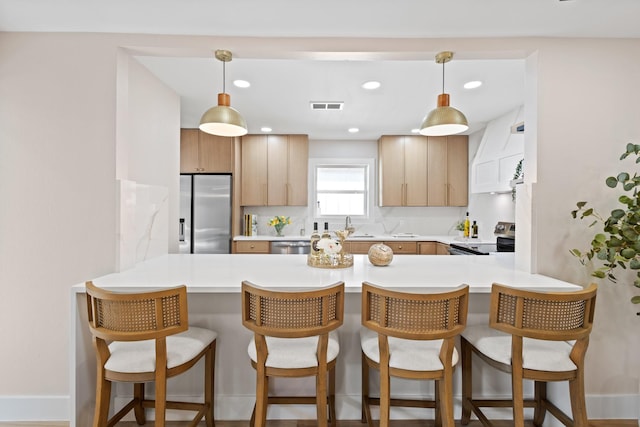 10528 Swallow Ln, Dallas, TX 75218 - kitchen with stainless steel appliances, a peninsula, light countertops, a breakfast bar area, and recessed lighting