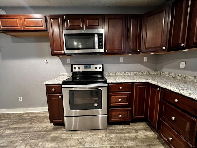 106 Lane St, Comanche, TX 76442 - kitchen featuring stainless steel appliances, light wood-type flooring, baseboards, dark brown cabinets, and light stone counters