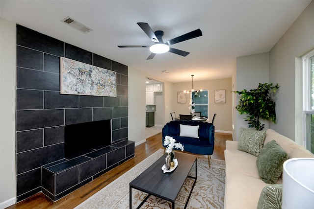 7333 Pensacola Ave, Fort Worth, TX 76116 - living area featuring wood finished floors, ceiling fan, baseboards, a tiled fireplace, and a chandelier
