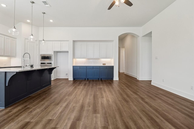 2208 13th St, Argyle, TX 76226 - kitchen with backsplash, a ceiling fan, white cabinetry, arched walkways, and dark wood-type flooring