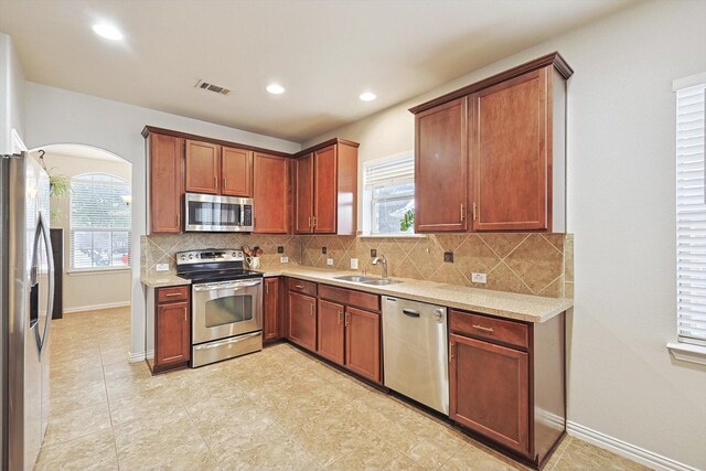 7009 Bishop Pine Rd, Denton, TX 76208 - kitchen with stainless steel appliances, a sink, decorative backsplash, arched walkways, and baseboards