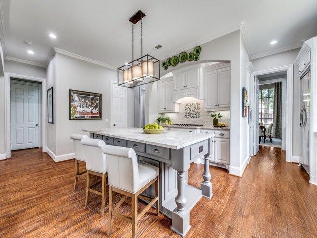11483 Mirage Ln, Frisco, TX 75033 - kitchen with a breakfast bar area, baseboards, a center island, wood finished floors, and recessed lighting