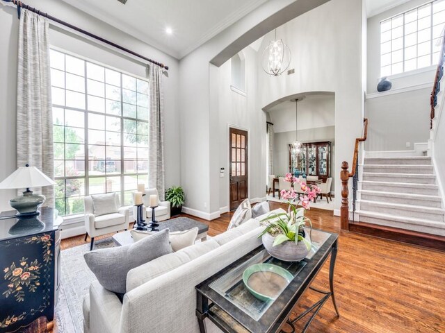11483 Mirage Ln, Frisco, TX 75033 - living room featuring a chandelier, arched walkways, baseboards, a high ceiling, and stairs
