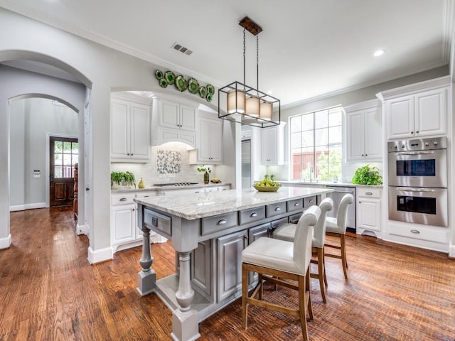 11483 Mirage Ln, Frisco, TX 75033 - kitchen with stainless steel appliances, white cabinetry, a center island, backsplash, and ornamental molding