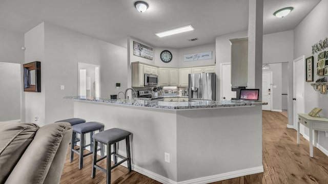 229 Willow Creek Dr, Weatherford, TX 76085 - kitchen with appliances with stainless steel finishes, a peninsula, light stone counters, light wood-style flooring, and a high ceiling