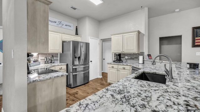 229 Willow Creek Dr, Weatherford, TX 76085 - kitchen with stainless steel fridge with ice dispenser, a sink, light stone counters, and backsplash