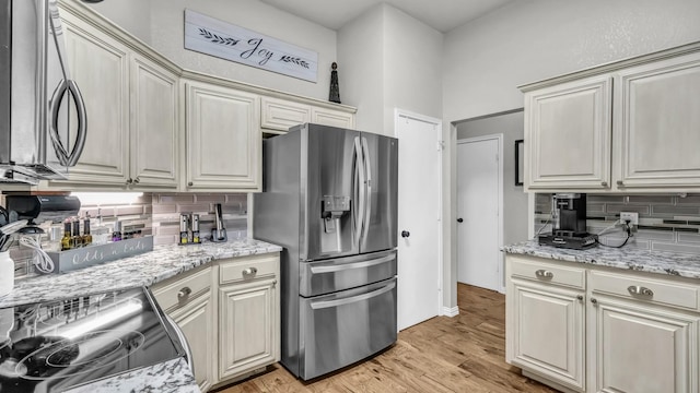 229 Willow Creek Dr, Weatherford, TX 76085 - kitchen featuring stainless steel fridge, backsplash, electric range oven, light wood-style floors, and light stone counters