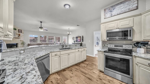 229 Willow Creek Dr, Weatherford, TX 76085 - kitchen with appliances with stainless steel finishes, a sink, cream cabinets, decorative backsplash, and ceiling fan