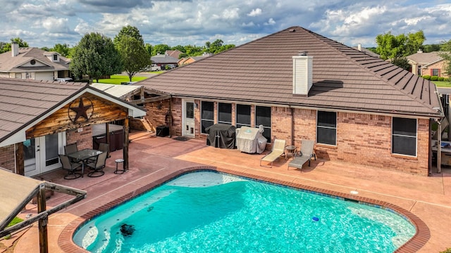 229 Willow Creek Dr, Weatherford, TX 76085 - rear view of house with a patio, brick siding, a tiled roof, and an outdoor pool