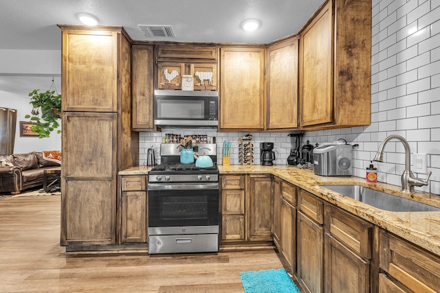 201 E Pearl St, Celeste, TX 75423 - kitchen with appliances with stainless steel finishes, a sink, tasteful backsplash, light stone counters, and light wood-type flooring