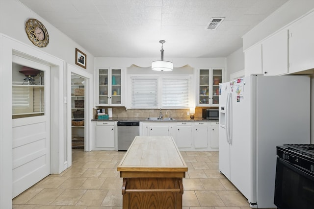 1425 W Gambrell St, Fort Worth, TX 76115 - kitchen featuring stainless steel appliances, a sink, white cabinets, tasteful backsplash, and glass insert cabinets