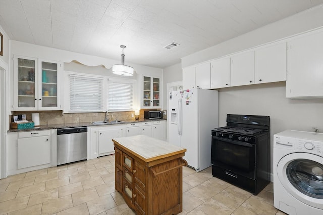 1425 W Gambrell St, Fort Worth, TX 76115 - kitchen with washer / clothes dryer, appliances with stainless steel finishes, a sink, and white cabinetry