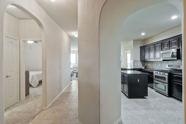 5420 Chinkapin Ln, Fort Worth, TX 76244 - kitchen featuring appliances with stainless steel finishes, arched walkways, a center island, dark countertops, and decorative backsplash