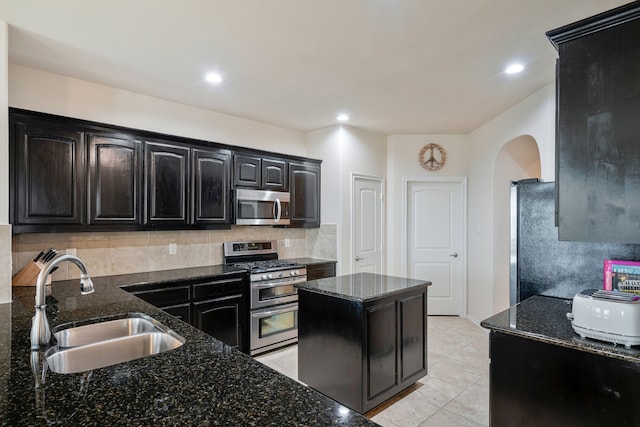 5420 Chinkapin Ln, Fort Worth, TX 76244 - kitchen featuring appliances with stainless steel finishes, a sink, arched walkways, dark stone counters, and decorative backsplash