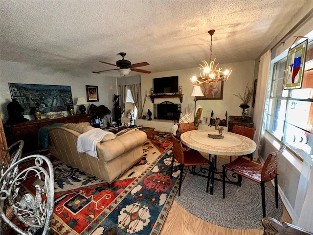 1002 Wrights W, Comanche, TX 76442 - living room featuring a textured ceiling, healthy amount of natural light, wood finished floors, a ceiling fan, and a chandelier