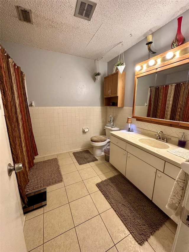 1002 Wrights W, Comanche, TX 76442 - full bathroom with tile walls, tile patterned floors, vanity, toilet, and a wainscoted wall