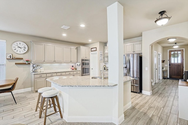 9117 Conroe Dr, Denton, TX 76226 - kitchen with stainless steel appliances, wood tiled floors, arched walkways, a sink, and baseboards