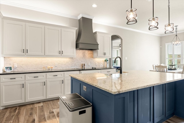 2141 Vanderbilt Dr, Weatherford, TX 76088 - kitchen featuring custom exhaust hood, white cabinets, arched walkways, tasteful backsplash, and a center island with sink
